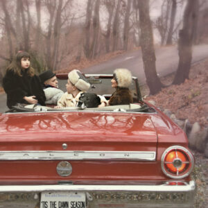 a family dressed in furs, sitting in a red convertible with a license plate that says "Tis the damn season"