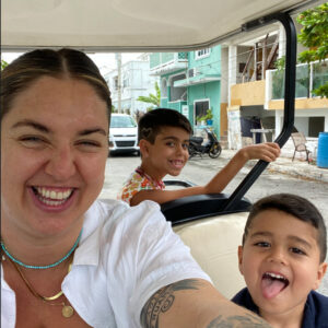 a woman and two children smile at the camera from a golf cart