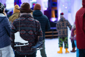 ice skates hang over a person's shoulders by their laces at their back