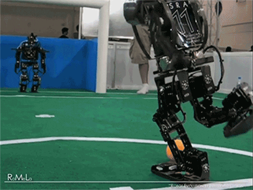 a gif of a robot kicking a ball at another robot that falls onto the ground in its effort to stop the ball